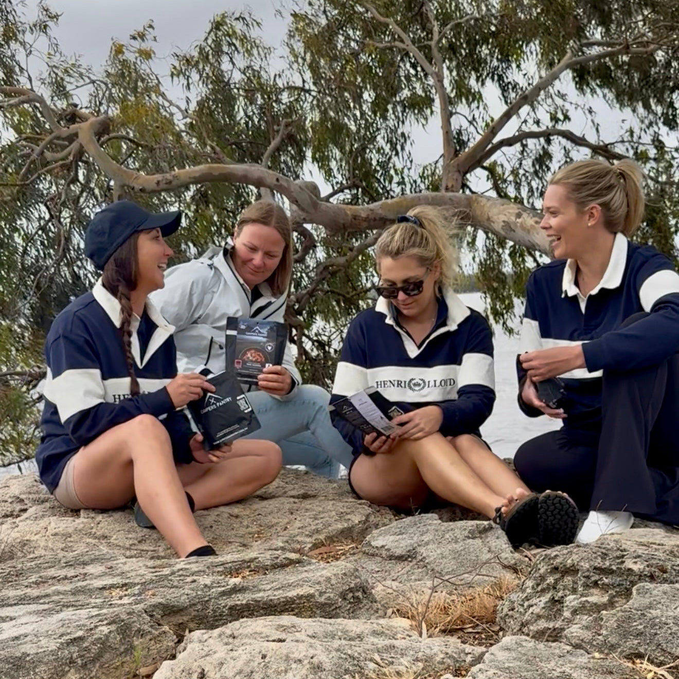 Team Atlantic Waterbirds in matching uniforms sitting on rocks outdoors, holding the best lightweight nutrition hiking food Campers Pantry.