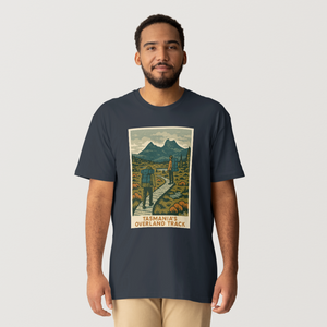 A black t-shirt featuring a graphic print of the Overland Track in Tasmania with a mountainous landscape and a hiker on the trail.