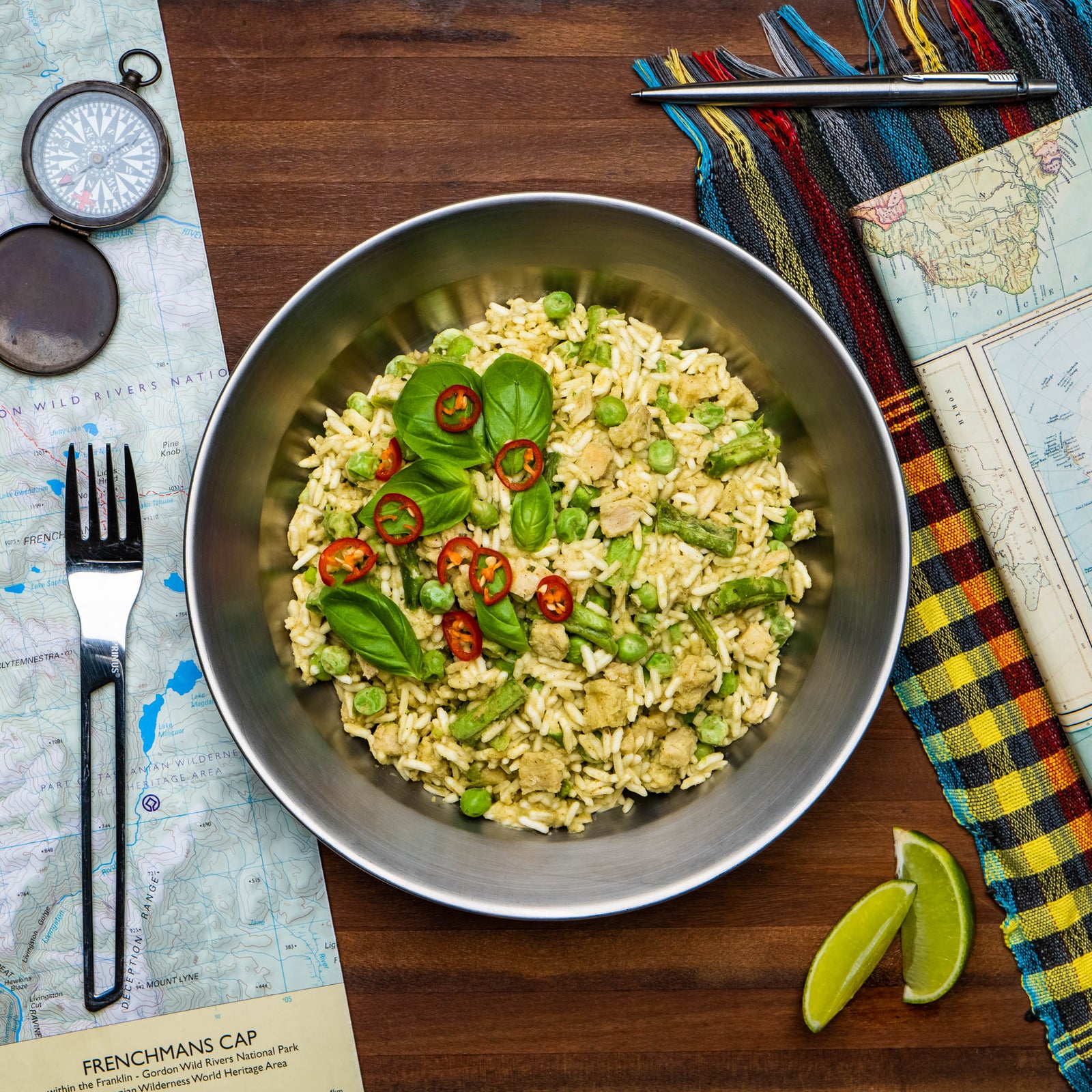 A bowl of Campers Pantry Green Thai Chicken Curry EXPEDITION hiking food meal, with a map and a piece of lime on the side, indicative of a travel-ready, freeze-dried meal product.
